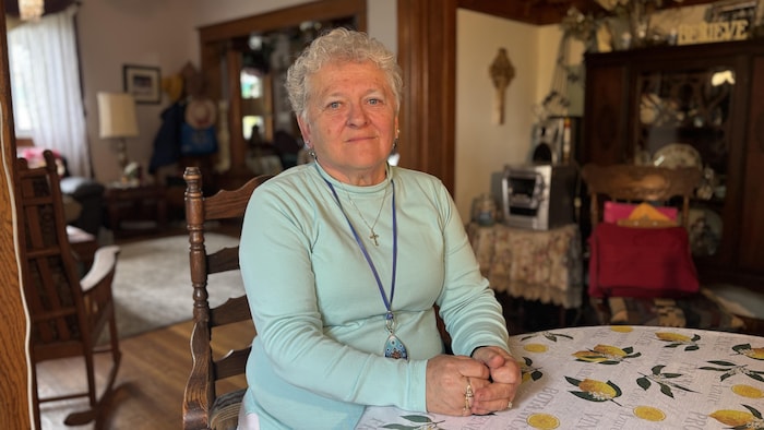 Mary Jane Thompson est assise dans son salon, les bras sur la table à manger.