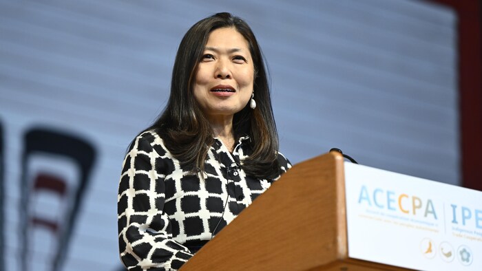 Mary Ng parle debout derrière un lutrin.