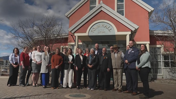 Une quinzaine de personnes sont devant l'hôtel de ville de Tumbler Ridge.