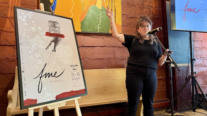 Maryline Lacombe, debout au micro, s'adresse aux gens, le bras droit en l'air.