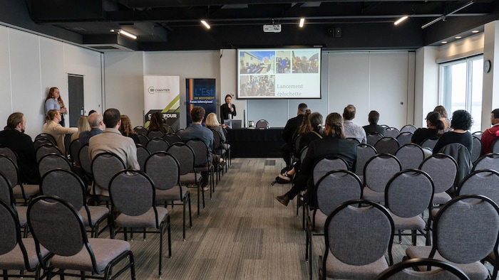 Des gens assistent à une conférence dans une salle.