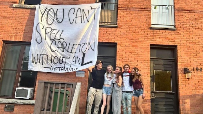 Des étudiants devant une pancarte.