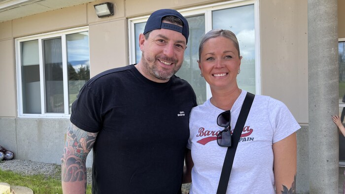Un couple souriant devant une maison.