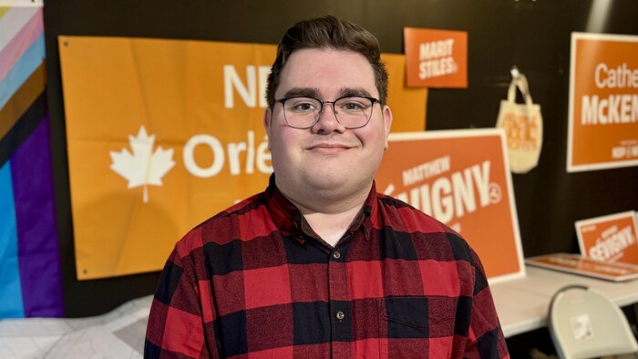 Portrait de Matthew Sévigny devant des pancartes du N P D de l'Ontario.