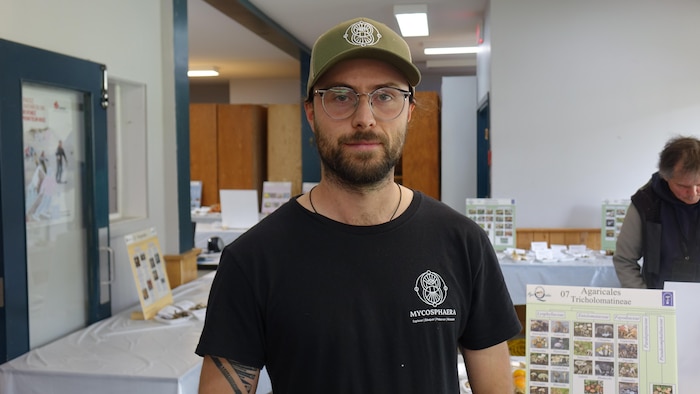 Portrait de Mathias Rocheleau-Duplain devant des tables d'informations sur les champignons.