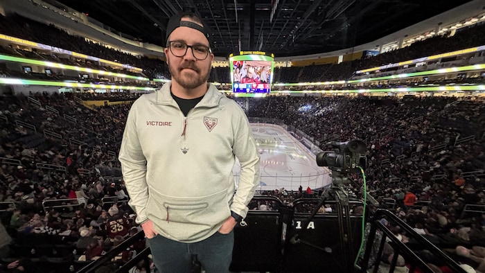 Portrait de Mathieu Boulianne, debout, au Centre Vidéotron. La foule est assise dans les gradins en arrière.