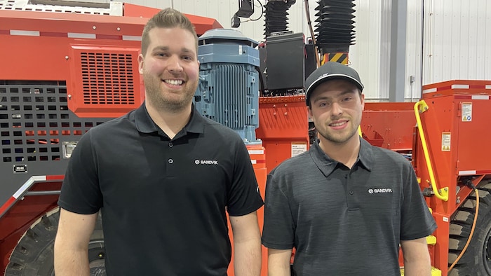 Mathieu Dugas, gérant d'atelier, et Nygel Chouinard, technicien d'atelier, posent devant une des machines dont Sandvik fait l'entretien mécanique.
