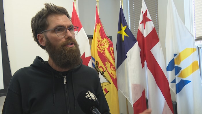 Un homme devant des drapeaux.