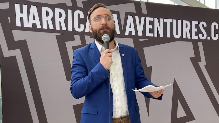 Mathieu Proulx, notes en main, parle au micro pour s'adresser aux gens dans la salle.