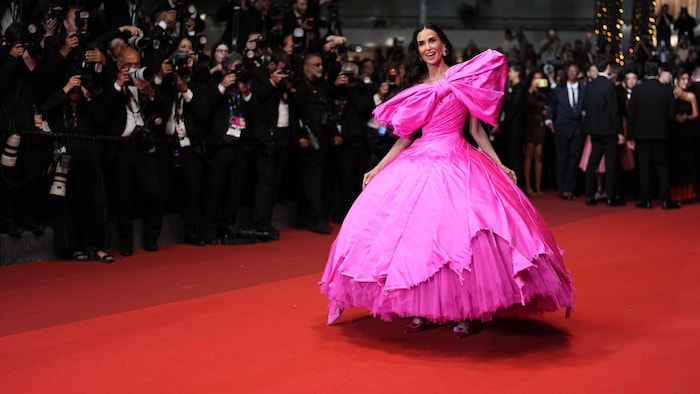 Demi Moore porte une robe rose sur un tapis rouge. 