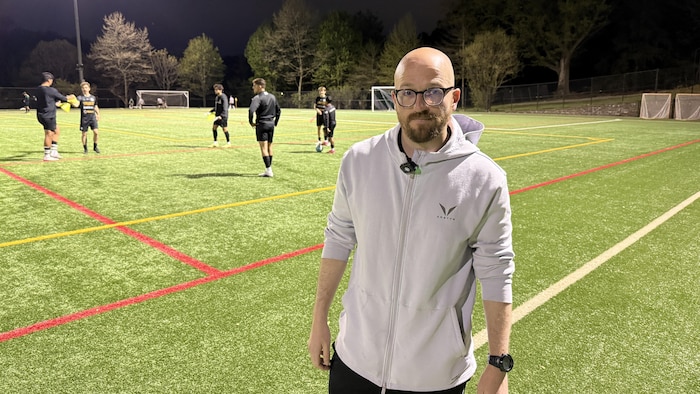 Un homme en bordure d'un terrain de soccer.