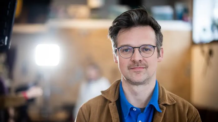 Un homme portant des lunettes sourit.