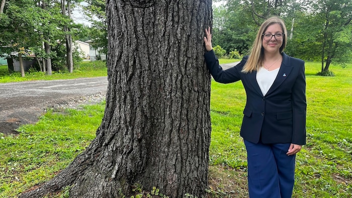 La candidate libérale dans Bellefeuille, Maud Laporte-Roy, appuyée sur un arbre.