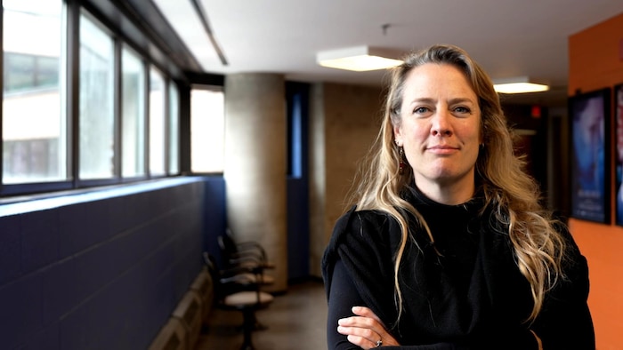 Une femme prend la pose, les bras croisés.