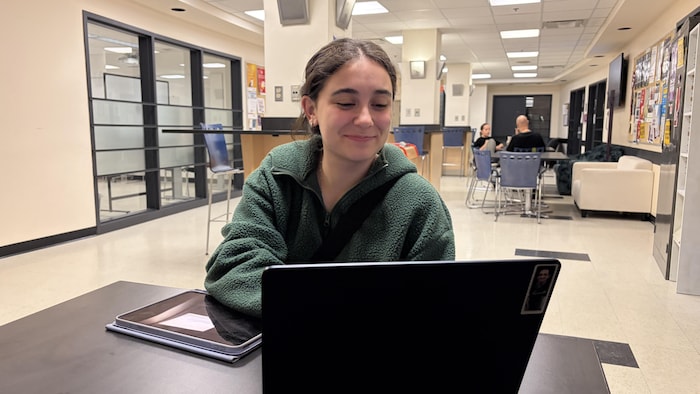 Une jeune femme est assise à une table devant un ordinateur portable.