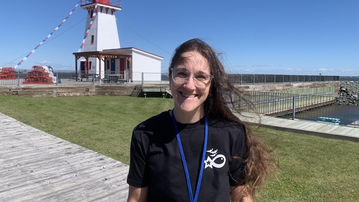 Une femme dehors, debout, devant un phare à Shippagan.