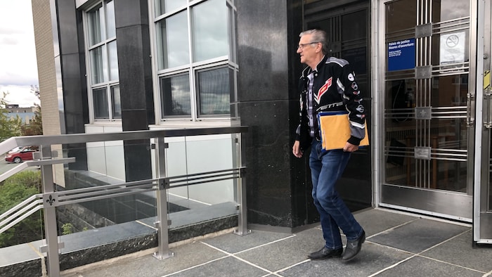 Un homme sort du palais de justice, des documents à la main.