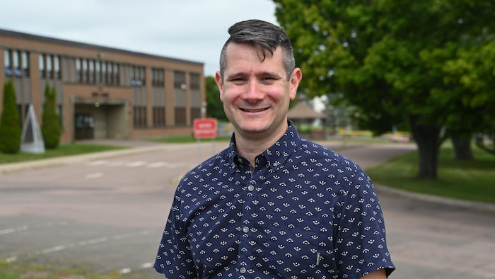 Une personne souriante devant une école.