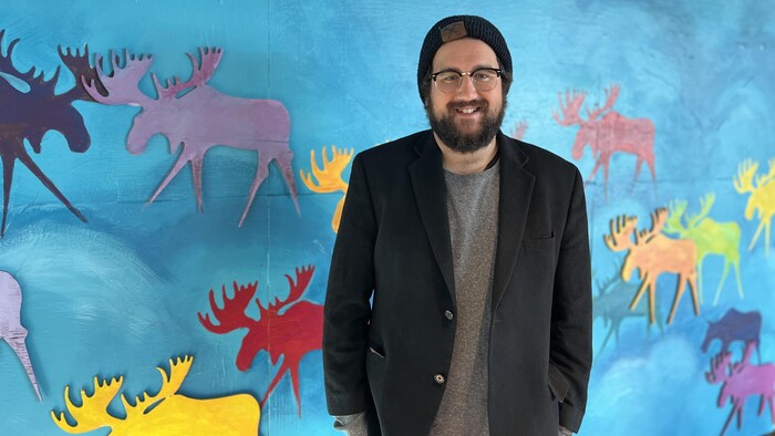 Maxime Dupuis pose devant le décor du Festival du cinéma international en Abitibi-Témiscamingue.