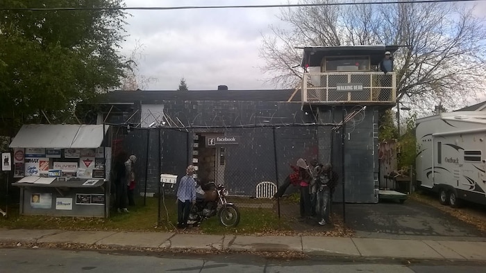 Une maison d'Halloween avec des zombies et une clôture.