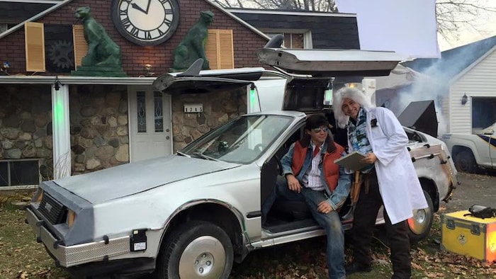 Deux hommes sont dans une voiture devant une maison.