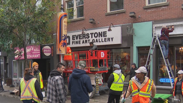 Des travailleurs s'affairent à transformer la devanture de magasins dans une rue de Montréal pour qu'elle ressemble à San Diego. 