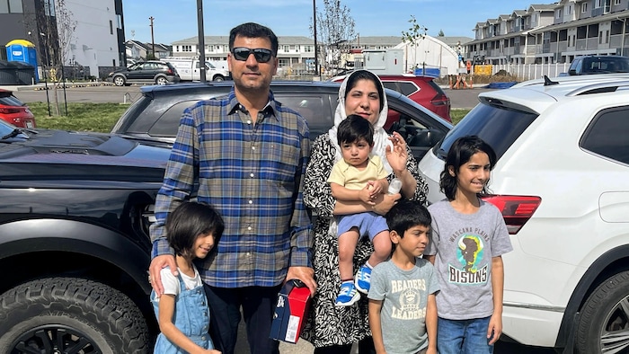 Maziash Samad accompagnée de son mari et de leurs quatre enfants, tous avec des sacs d'épicerie.