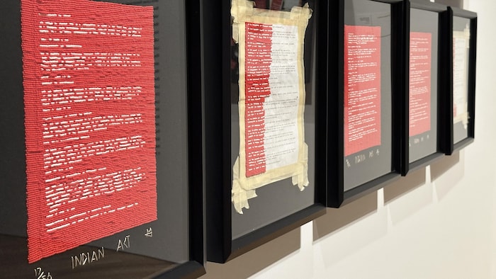 Des petites perles rouges et blanches sont assemblées de manière à représenter un papers écrit.