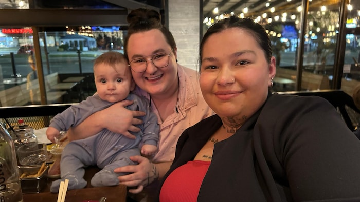 Deux femmes souriantes en compagnie d'un bébé dans un restaurant