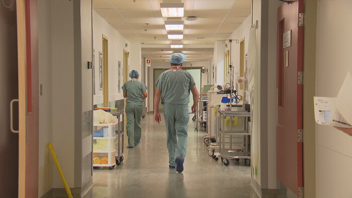 Un médecin marche dans un corridor d'hôpital.