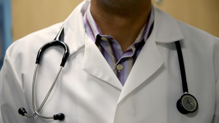 Un médecin vêtu d'un sarrau, avec un stéthoscope autour du cou. 