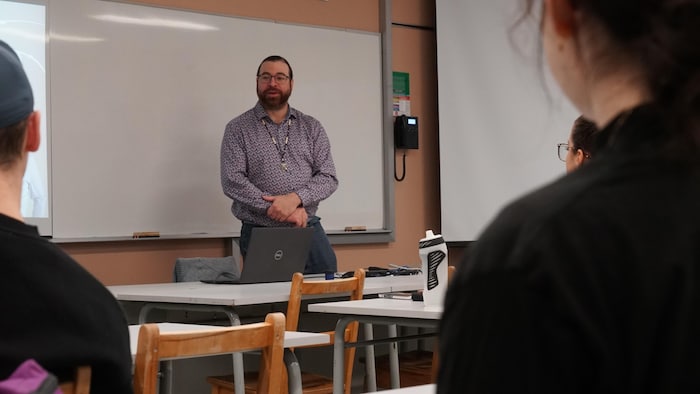 Un homme parle devant une classe.