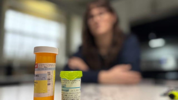 Deux bouteilles en avant-plan, une femme à l'image floue assise à un comptoir.