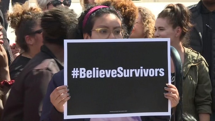 Une femme tient une pancarte, où il est écrit « believe survivors », c'est à dire « croyez les survivantes ».
