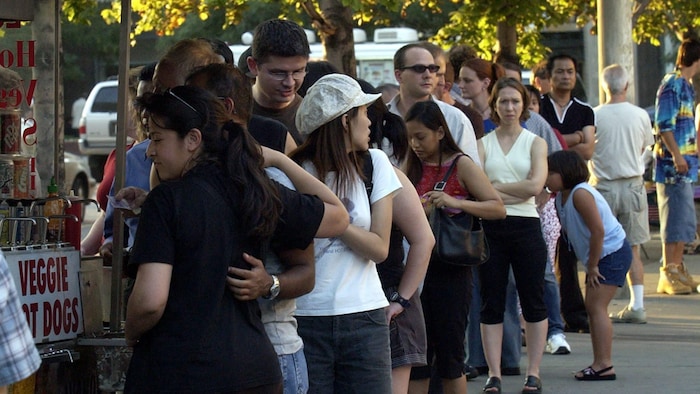 Des personnes font la file en attendant d’être servies à un kiosque extérieur.