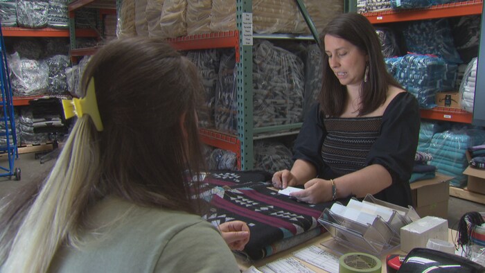 Deux femmes dans un entrepôt rempli de couvertures aux motifs autochtones.
