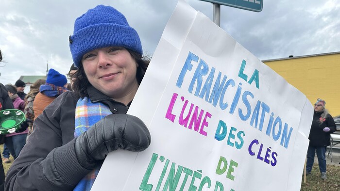 Une femme tient une affiche qui dit : « La francisation, l'une des clés de l'intégration ».