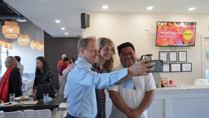 Kumuha ng selfie si Kevin Lamoureux kasama si Mélanie Joly at isang Pilipinong lalaki sa loob ng restawran.