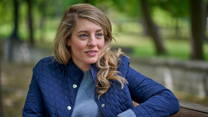 Mélanie Joly est assise sur un banc.