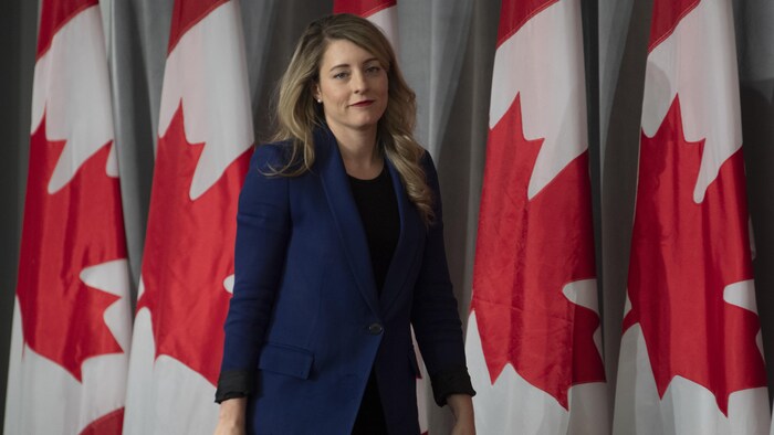 Elle marche devant des drapeaux canadiens.