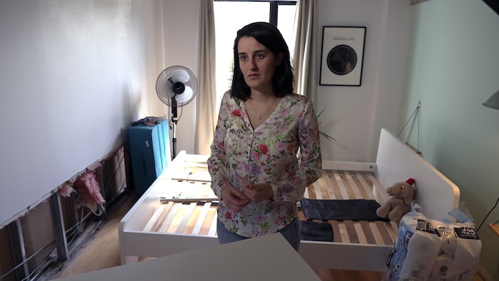 Une femme debout dans une chambre complètement détruite par une inondation.