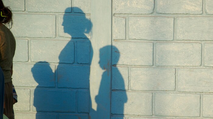 L'ombre d'une femme et de ses enfants sur un mur de ciment