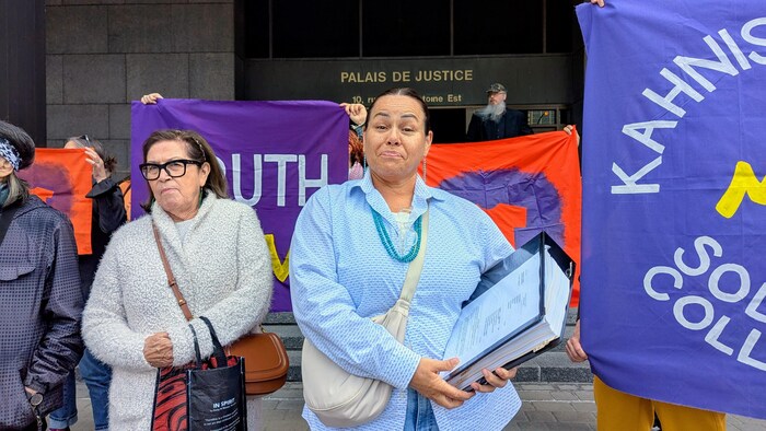Kwetiio tient un très gros cartable devant le palais de justice de Montréal, le 13 juin 2025.