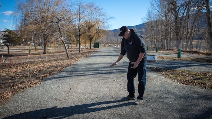 Mike Goetz montrant un niveau avec la main a un mètre du sol dans un parc à Merritt. 