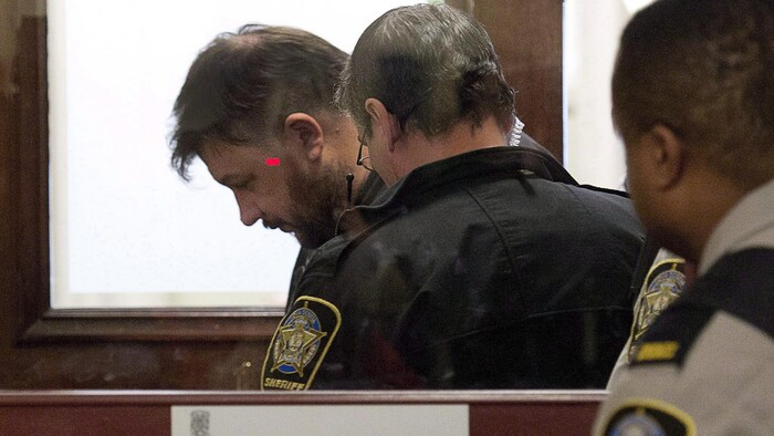 Gros plan de Christopher Fattore dans le box des accusés d'un tribunal.