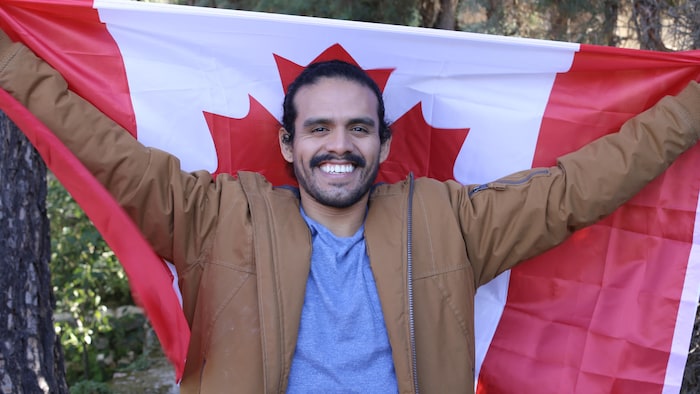 Un homme latino tient un drapeau canadien