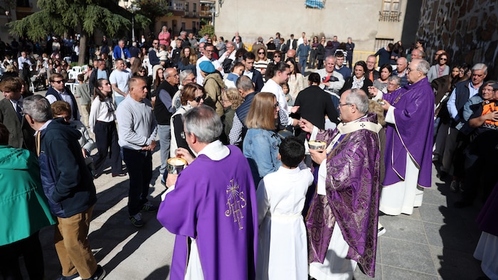 Des prêtres donnent l'eucharistie dehors.