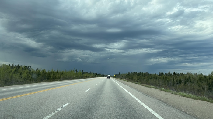 Un nuage noir se forme au-dessus d'une route.