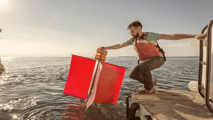 Un homme fait descendre un objet dans l'eau d'un lac.