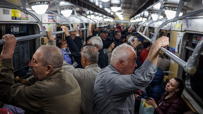 Des gens debout ou assis dans un wagon de métro.